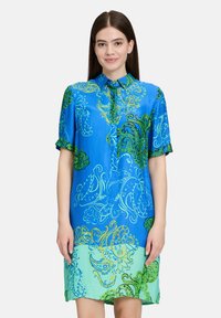 Abito a maniche corte blu e verde con motivi paisley. Presenta un colletto con bottoni, tessuto morbido e un design al ginocchio.