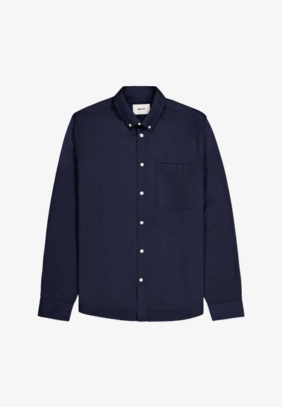 Donkerblauwe langmouwenshirt van katoen. Het heeft een button-down kraag, witte knopen en een enkele borstzak aan de linkerkant.