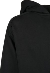 Tela de sudadera negra que muestra la parte superior de la espalda y la capucha adherida con costuras visibles.