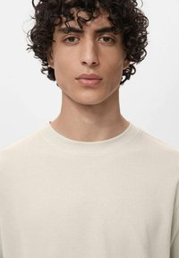 Lys beige ribbet sweatshirt med rund halsudskæring og lange ærmer, der har et struktureret stof og en afslappet pasform.