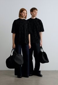 Μαύρα κοντομάνικα πουκάμισα με υφή με μοτίβο, συνδυασμένα με σκούρα τζιν παντελόνια και μαύρα τσαντάκια. Μινιμαλιστικός σχεδιασμός με σύγχρονη εμφάνιση.