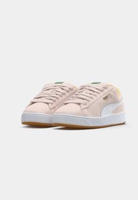 Baskets Puma Suede rose clair avec bande blanche, semelle en gomme et intérieur beige, vues de face sur fond blanc.