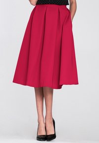 Spódnica midi plisowana w intensywnym magenta, wykonana z g�ładkiego materiału. Posiada boczne kieszenie i sięga poniżej kolan. Zestawiona z czarnymi szpilkami.