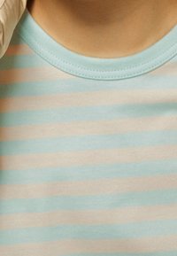 Randig t-shirt med ett mönster i ljusblått och beige. Har en mjuk och bekväm tygkvalitet samt en rund, ribbad halsringning.