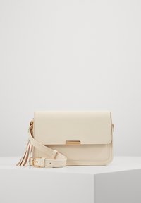 Krémozelená kabelka přes rameno z hladké kůže, se zapínáním na klopu, zlatými kovovými doplňky a dekorativním střapcem na pásku.