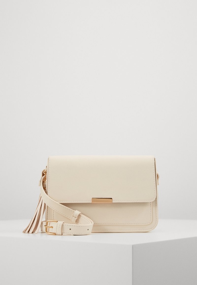 Krémozelená kabelka přes rameno z hladké kůže, se zapínáním na klopu, zlatými kovovými doplňky a dekorativním střapcem na pásku.