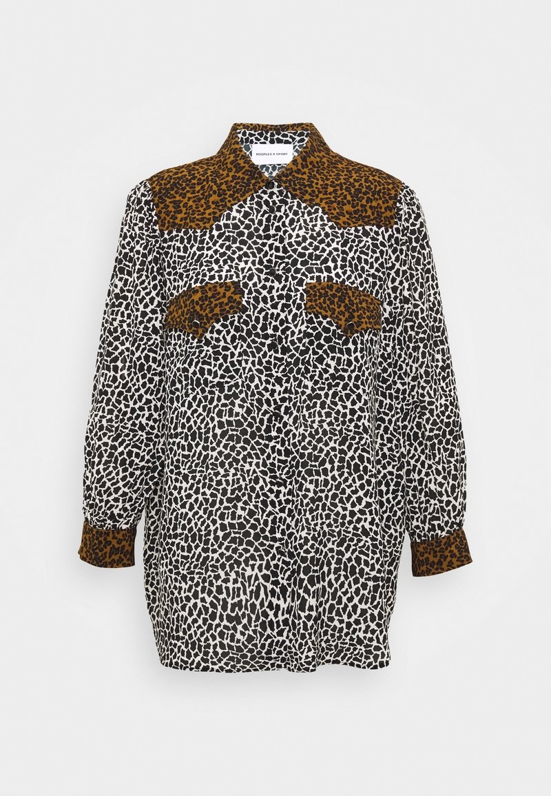 Chemise à manches longues avec des taches irrégulières noires et blanches et des détails imprimé léopard brun foncé sur le col, les poches poitrine et les poignets.