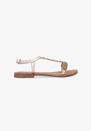 Gold-accented flat sandal with a metallic pink strap, T-shaped design, and soft brown insole. Adjustable ankle strap for fit flexibility.