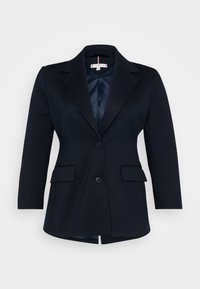 Blazer marine avec un design structuré, des revers en pointe, deux poches avant et une fermeture à un bouton. Doublure intérieure lisse.
