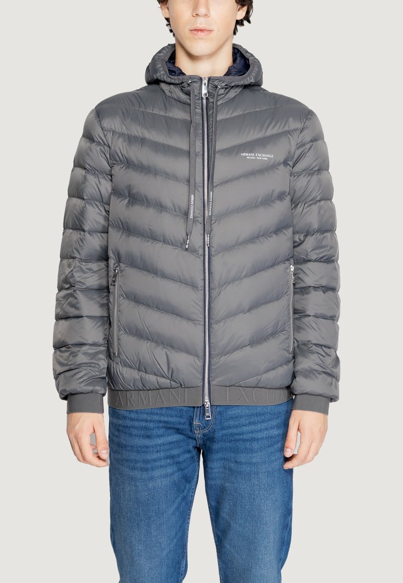 Chaqueta acolchada gris con capucha, que presenta un cierre frontal con cremallera, puños elásticos y un acabado texturizado. Logotipo mostrado en el pecho y la cinturilla.