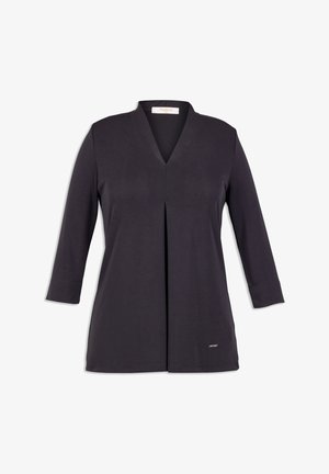 Túnica negra con escote en V, mangas largas y un pliegue frontal. Tejido suave con una textura lisa. Presenta una pequeña etiqueta de la marca en el dobladillo.