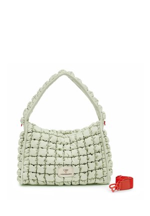 Bolso acolchado verde claro con un patrón de cuadrícula, asa corta, etiqueta frontal y una correa de hombro roja desmontable separada en el lateral.