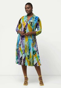 Vestido colorido y estampado con cuello, mangas tres cuartos y dobladillo acampanado, hecho de una tela ligera y texturizada en azul, amarillo y morado.