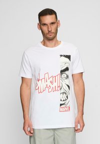 Hvid bomulds t-shirt med et tegneserie-inspireret grafik af et ansigt og teksten "SMASH!" i rødt. Inkluderer en mærket "MARVEL" label.