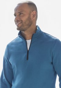 Blue fleece pullover with a half-zip collar and long sleeves. Smooth texture, featuring a subtle sheen and minimal stitching details.