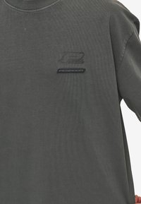 Mørkegrå bomulds t-shirt med ribbet udskæring, korte ærmer og sorte trykte logo akcenter foran.