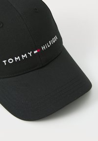 Casquette noire avec logo brodé "TOMMY HILFIGER" et accent rouge, blanc et bleu. Fabriquée en tissu lisse avec une visière incurvée.
