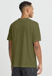 T-shirt a maniche corte verde oliva con scollatura rotonda e maniche arrotolate, realizzato in un tessuto liscio con un taglio rilassato.