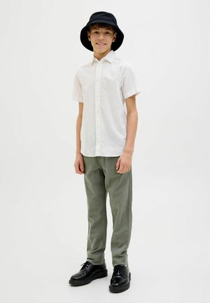 Chemise blanche à manches courtes avec boutons, pantalon vert olive, chapeau seau noir et chaussures noires. Design simple avec une coupe décontractée et une texture lisse.