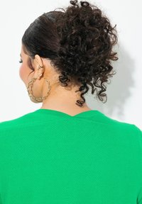 Grön nät-topp med V-ringning, strukturerad tyg och korta ärmar. Stora örhängen i guldkedja accentuerar looken.