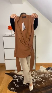 Asmuo laiko sukrauto raudono bezdirbo viršūnės su etikete kambaryje, kuriame yra baltos spintelės, oranžinė lempa ir karvės odos kilimas ant medinių grindų.