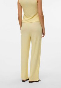 Débardeur texturé jaune et pantalon large assorti, tous deux en matériau léger, avec une coupe décontractée et un motif subtil.