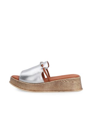 Silberne Sandale mit Riemen, braun gepolsterte Innensohle, Holzoptik-Plateausohle und dünnem braunem elastischem Riemen vorne.