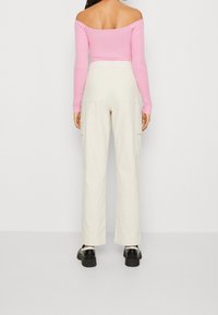 Ljusrosa ribbad off-shoulder topp, kombinerad med hög midja vita cargobyxor, med sidofickor och rak bendesign, bärs med svarta skor.