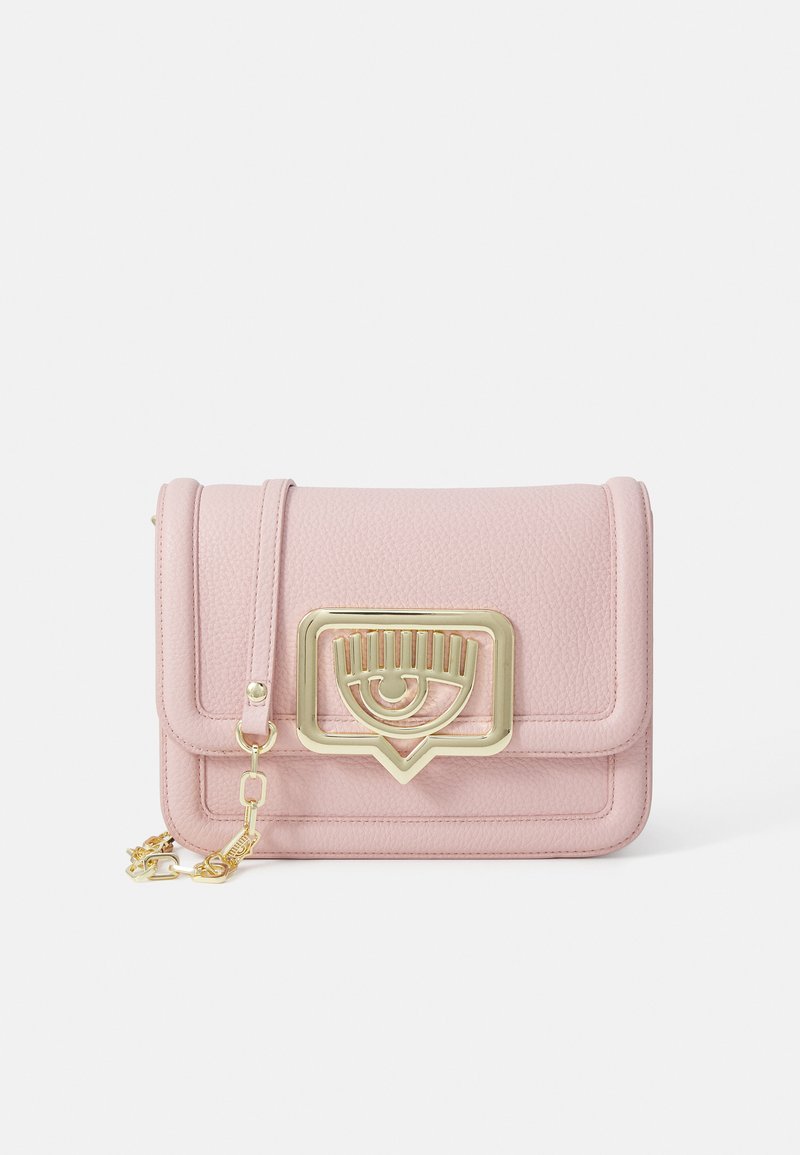 Piccola borsa a tracolla in pelle rosa texturizzata con chiusura a occhio dorato e catena parziale dorata su sfondo bianco.