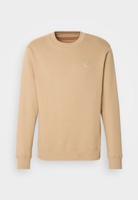 Sudadera beige hecha de una tela suave, con cuello redondo, mangas largas, puños acanalados y un minimalista bordado del logo en el pecho.