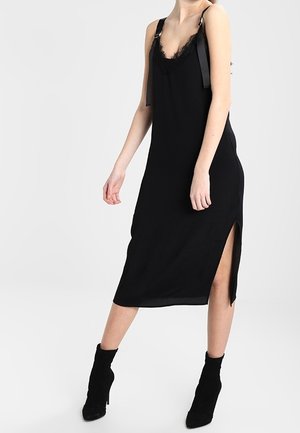 Czarna sukienka o długości do połowy łydki z koronkowym wykończeniem, regulowanymi ramiączkami i bocznym rozcięciem. Wykonana z miękkiej tkaniny, cechuje się minimalistycznym designem i gładką fakturą.