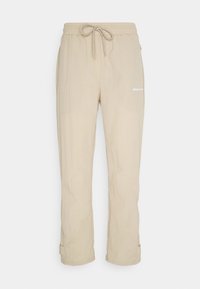 Beige lehké kalhoty s elastickým pasem, nastavitelnou šňůrkou, bočními kapsami a bílým potiskem loga na nohavici.