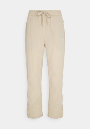 Beige lehké kalhoty s elastickým pasem, nastavitelnou šňůrkou, bočními kapsami a bílým potiskem loga na nohavici.