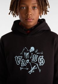 Černá mikina s kapucí, která má modrý grafický design se skeletony a skateboardy. Měkký materiál s klasickým střihem na přetahování a nastavitelnou kapucí.