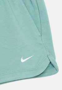 Pantalones cortos deportivos verde claro, fabricados en un material suave, con un logo blanco de Nike en el lado inferior y detalle de dobladillo cosido.