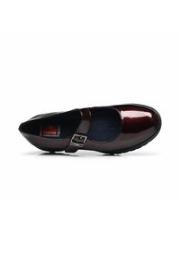 Zapato Mary Jane de cuero marrón con acabado brillante, punta redondeada y correa ajustable con hebilla metálica. Suela plana y texturizada.