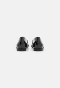 Pantofi din piele patent neagră, cu vârf rotunjit, toc jos și un design fără cusături. Suprafața este lucioasă, reflectând lumina.