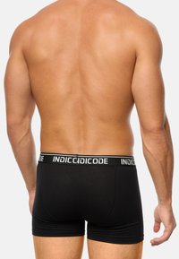 Bóxer negro con una cinturilla blanca de marca, tejido suave y un diseño ajustado, mostrando una vista trasera de la prenda.