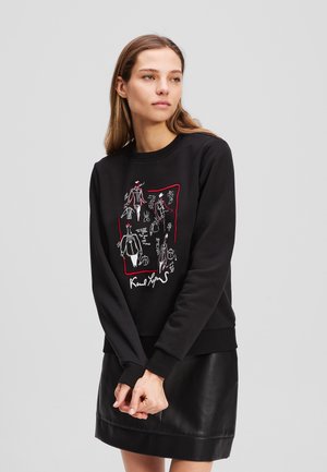 Schwarzer Sweatshirt mit einem bunten, detaillierten Grafikdesign, das Skizzen und Text umfasst, ergänzt durch gerippte Bündchen und Saum.