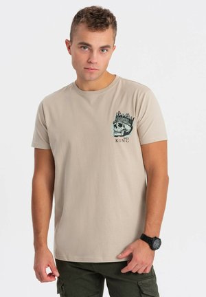 Beige bomulds T-shirt med korte ærmer og rund hals, med et kraniumdesign og en krone på venstre bryst.