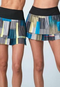 Due gonne plissettate con una vita nera. I pattern includono colori vivaci: blu, giallo e nero con vari disegni geometrici.