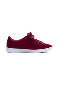 Velvet red sneaker with a white rubber sole, featuring large satin ribbon laces and subtle side stitching details. Rounded toe design.