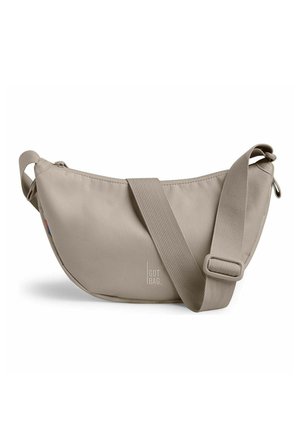 Sac bandoulière beige en forme de croissant avec une sangle large réglable et le logo "GOT BAG" centré à l'avant.