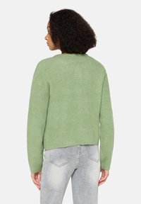 Jasnozielony, oversizowy sweter z dzianiny o okrągłym dekolcie i prążkowanym dole. Miękka faktura, opuszczone ramiona i luźny krój.