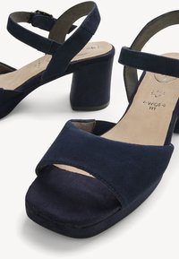Sandales bleu marine à bout ouvert avec talons blocs, brides à la cheville et semelles intérieures rembourrées étiquetées « largeur confort » pour un confort supplémentaire.