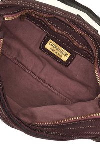 Interno di una borsa in pelle bordeaux con cerniera dorata e fodera a righe. Etichetta con la scritta "Caterina Lucchi, Made in Italy." Dettagli cuciti visibili.