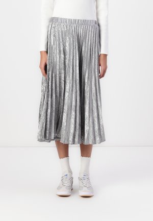 Pleated midi skirt in shiny silver fabric with a wide, elastic waistband. Paired with white, scalloped socks and grey sneakers.