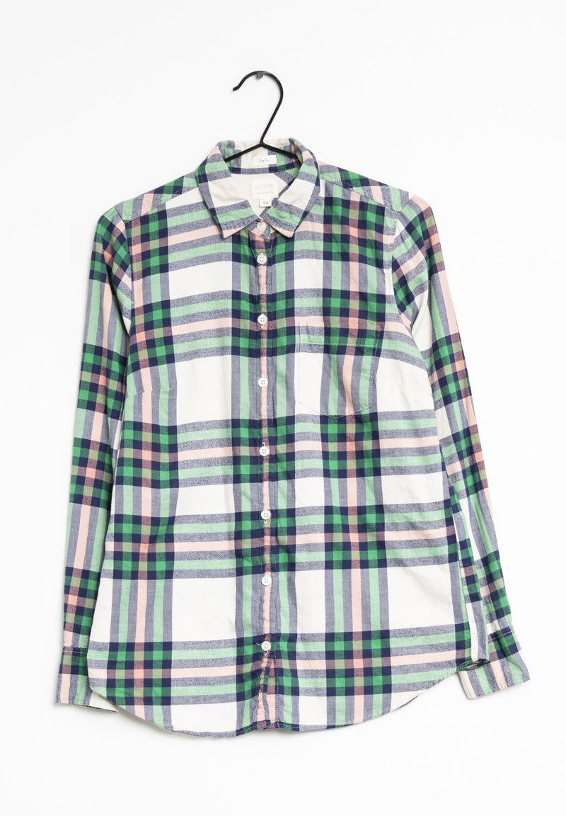 Chemise à manches longues boutonnée avec un motif à carreaux vert, bleu marine, rose et blanc, suspendue sur un cintre noir.