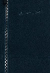 Jūrų pajėgų švarkas su užtrauktuku iki galo, tekstūruota medžiaga ir išsiuvinėtu "VAUDE" logotipu viršutiniame kairiajame kampe.