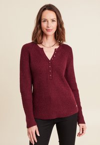 Maglione in maglia borgogna con scollo a V e cinque bottoni, texture a coste e maniche lunghe; il design presenta motivi diagonali.
